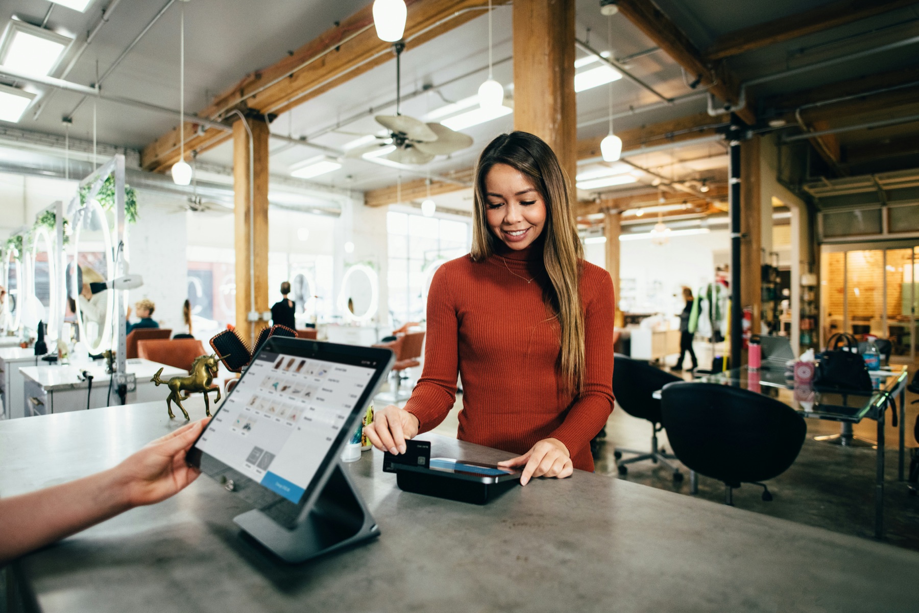 Shopper paying with a contactless card on a Shopify POS terminal at a modern retail checkout counter