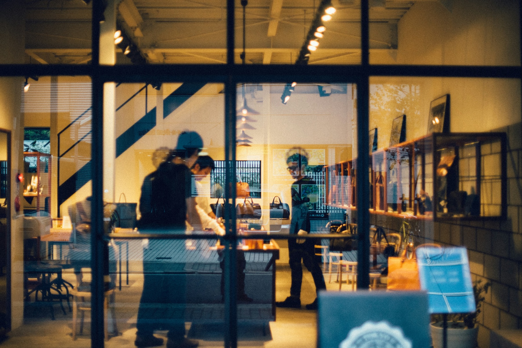 Boutique Shopify retail storefront at night seen through a window, with curated bags and merchandise on display